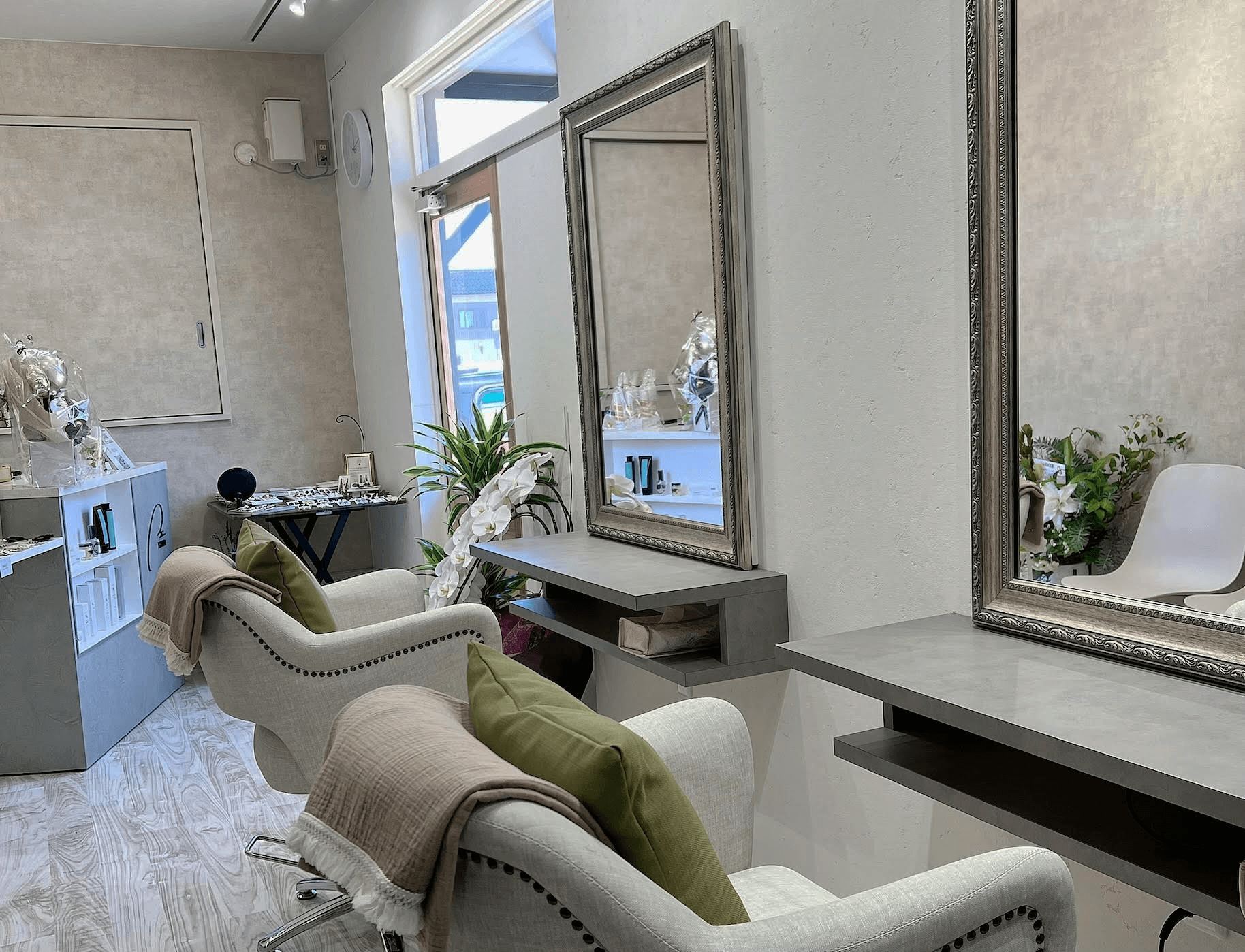 美容室のセット面。大きな鏡の前にベージュのチェアとグリーンのクッションが並び、明るく落ち着いた雰囲気の店内。